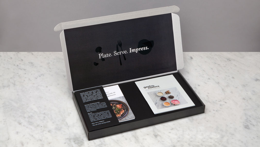 Gastronomics postage box interior with brochure and recipe cards on white marble