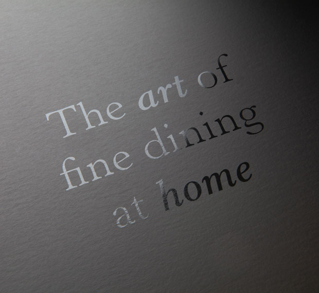 Gastronomics brand tag line the art of fine dining at home as black foild on black card