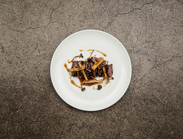 Still life photography of a plate of sliced seared steak